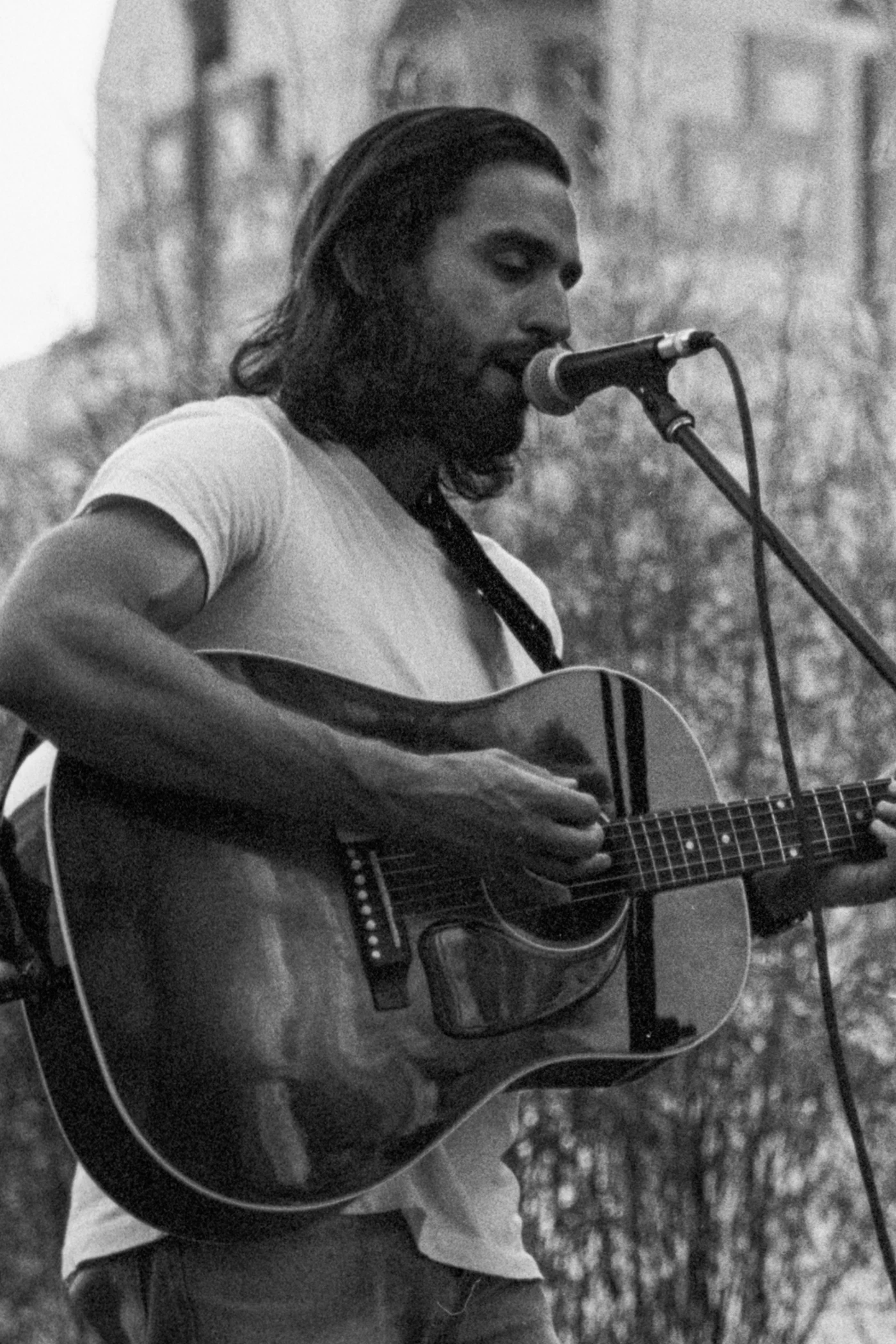 Dave Sonntag playing acoustic guitar and singing into a microphone outdoors